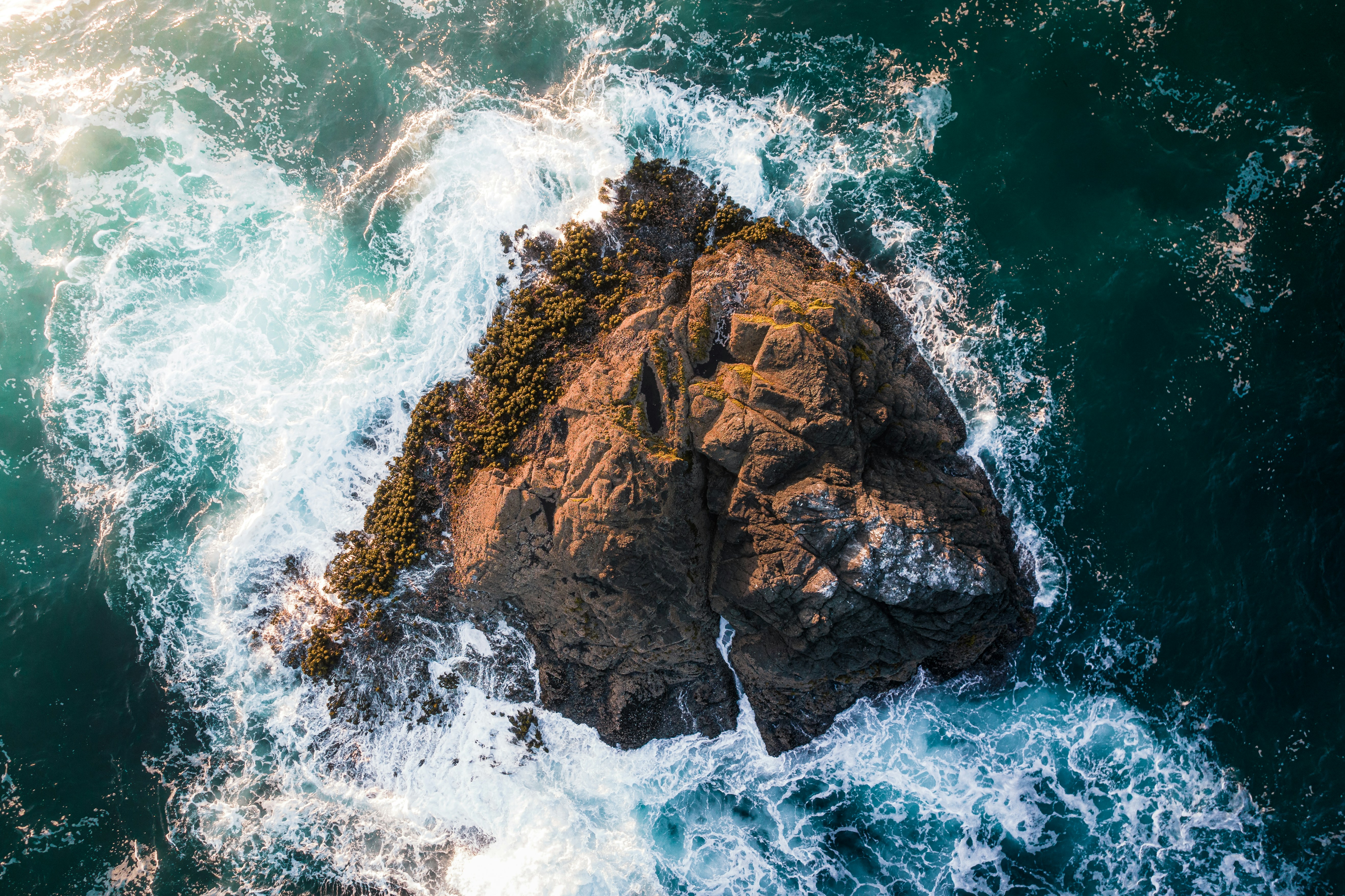 brown rock formation on body of water during daytime