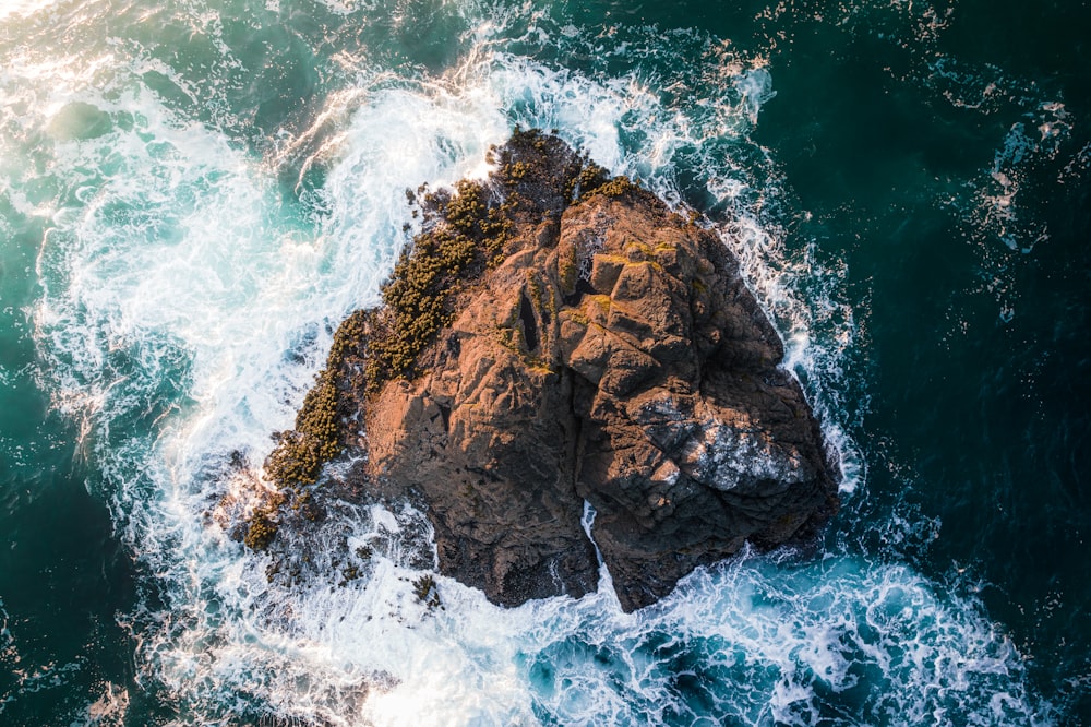 brown rock formation on body of water during daytime