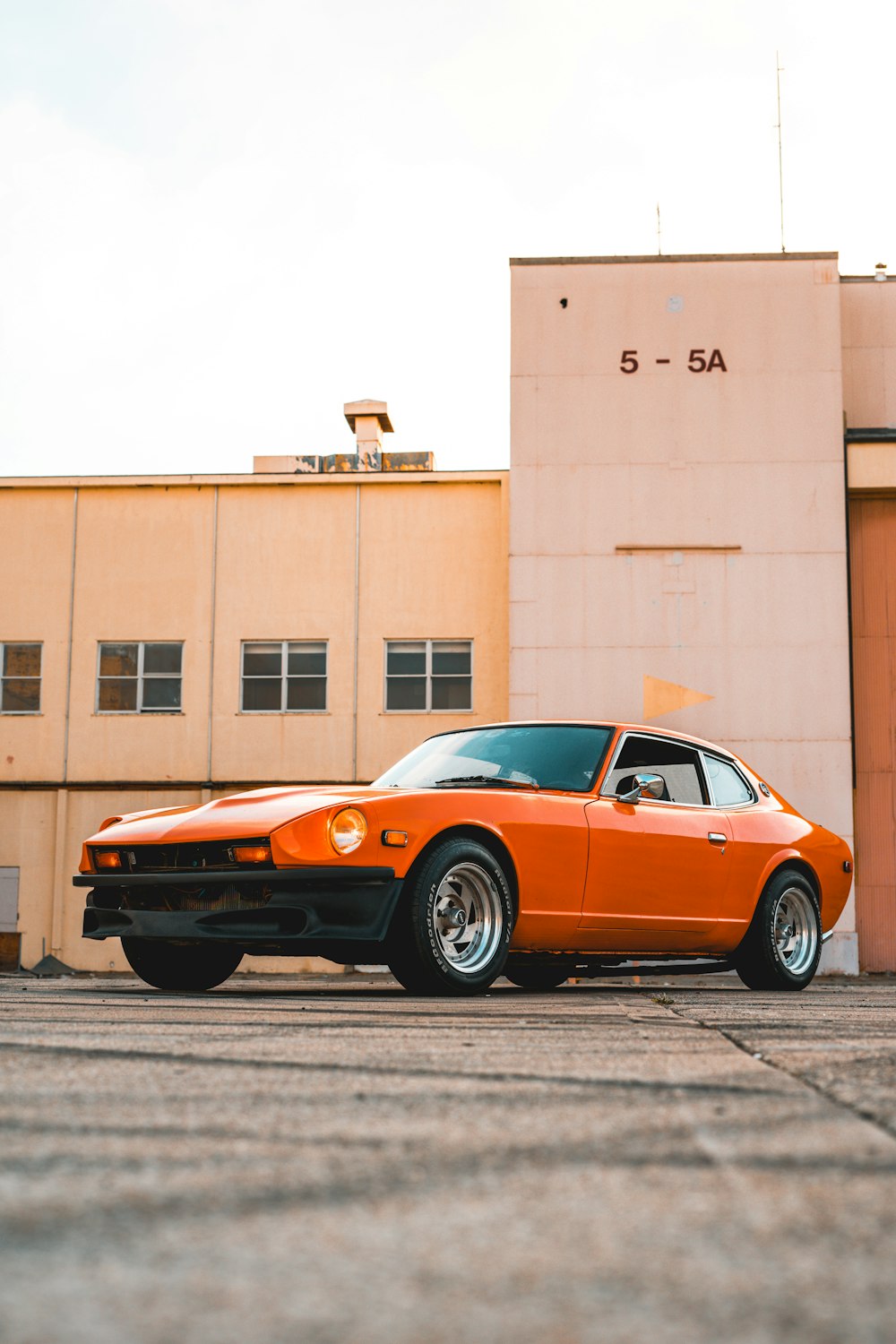 orange coupe parked beside brown building