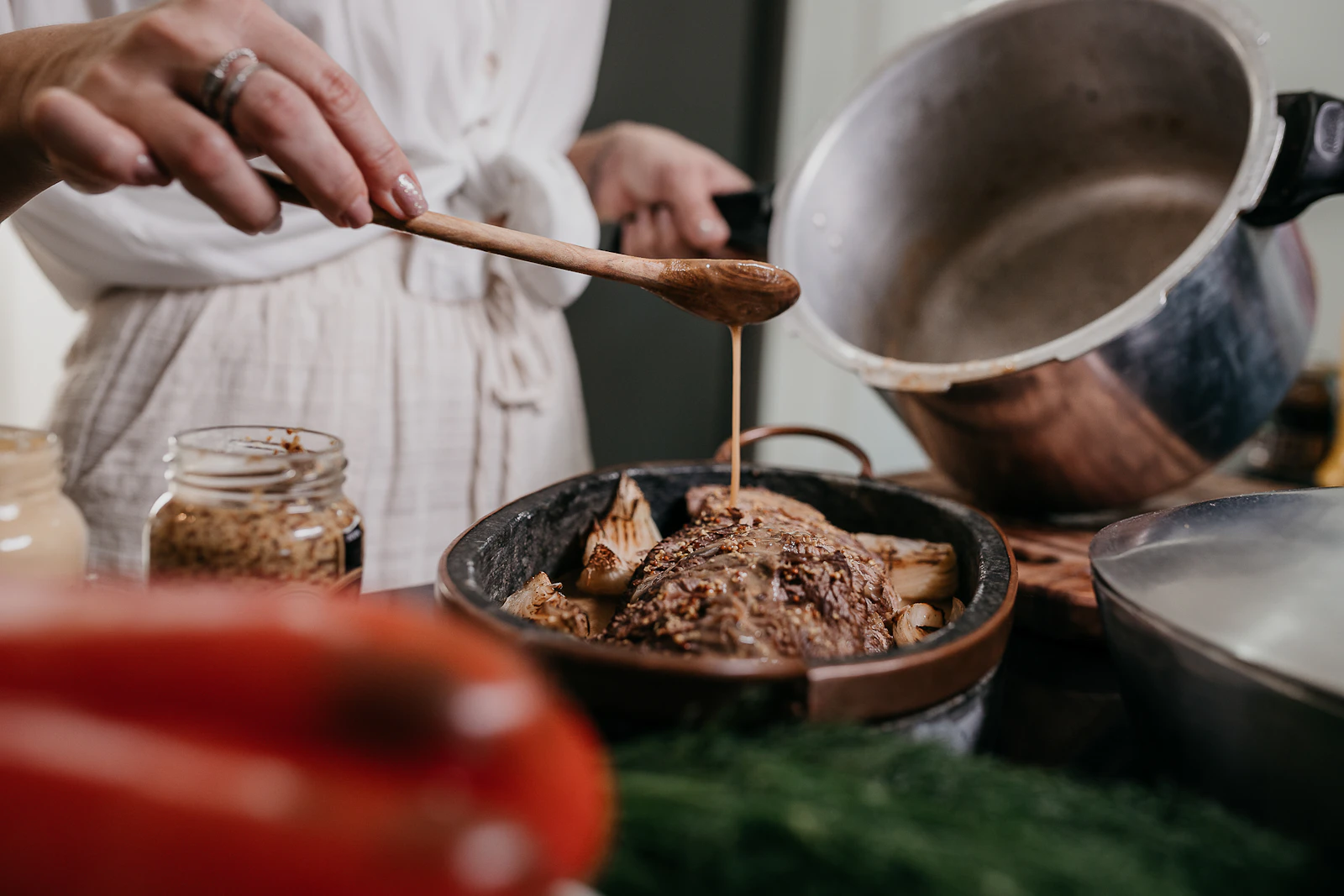 Hands stirring a simmering pot with a wooden ladle
