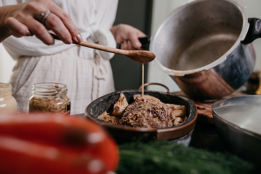 person holding brown wooden ladle