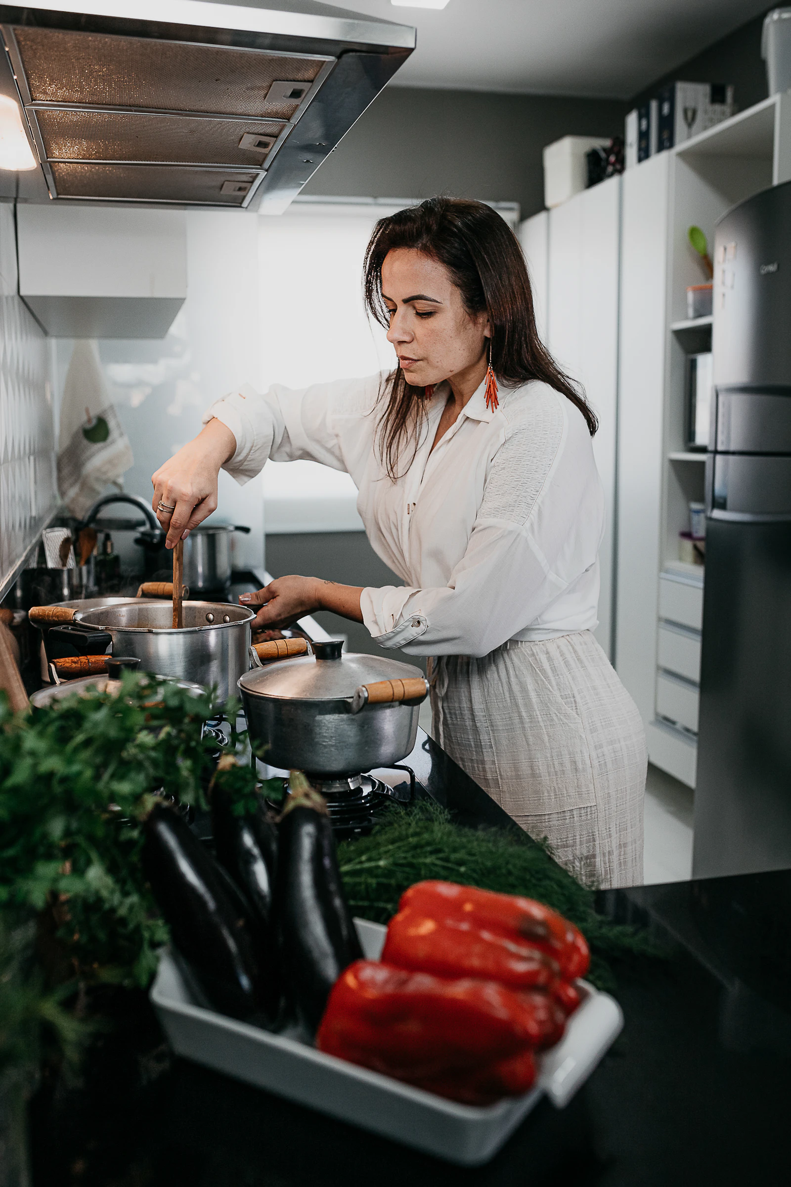 A woman in a white shirt holding a fresh green leafy vegetable, focused on food preparation.