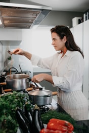 woman in white dress shirt holding stainless steel cooking pot