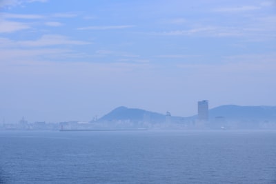 city skyline across the sea during daytime smoggy zoom background