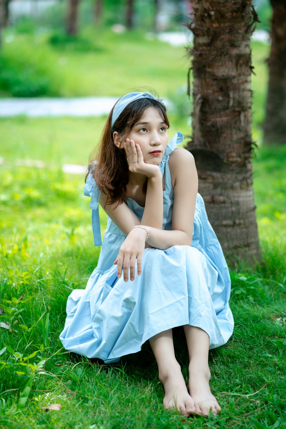 woman in blue dress sitting on green grass field during daytime