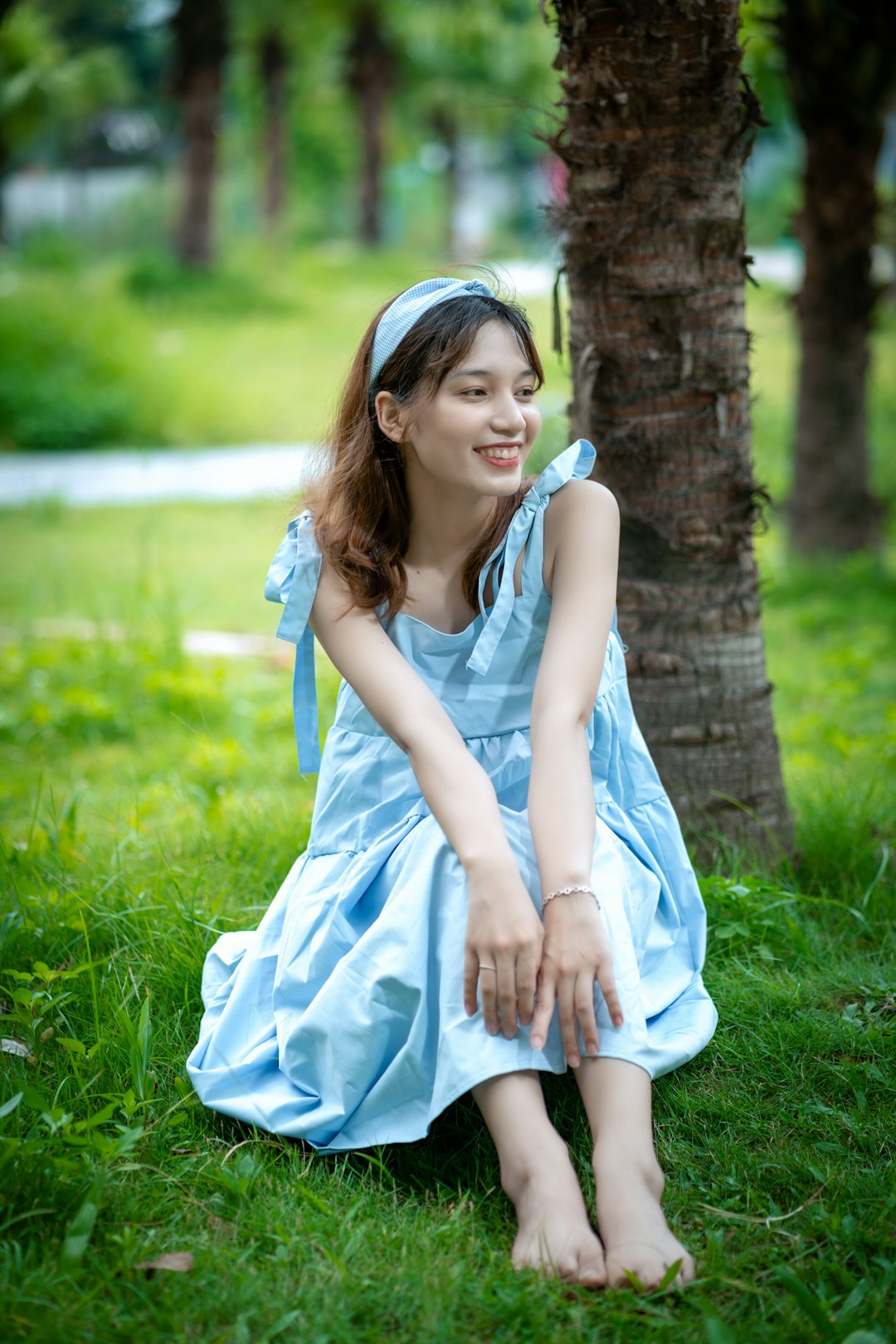 woman in blue sleeveless dress sitting on green grass field