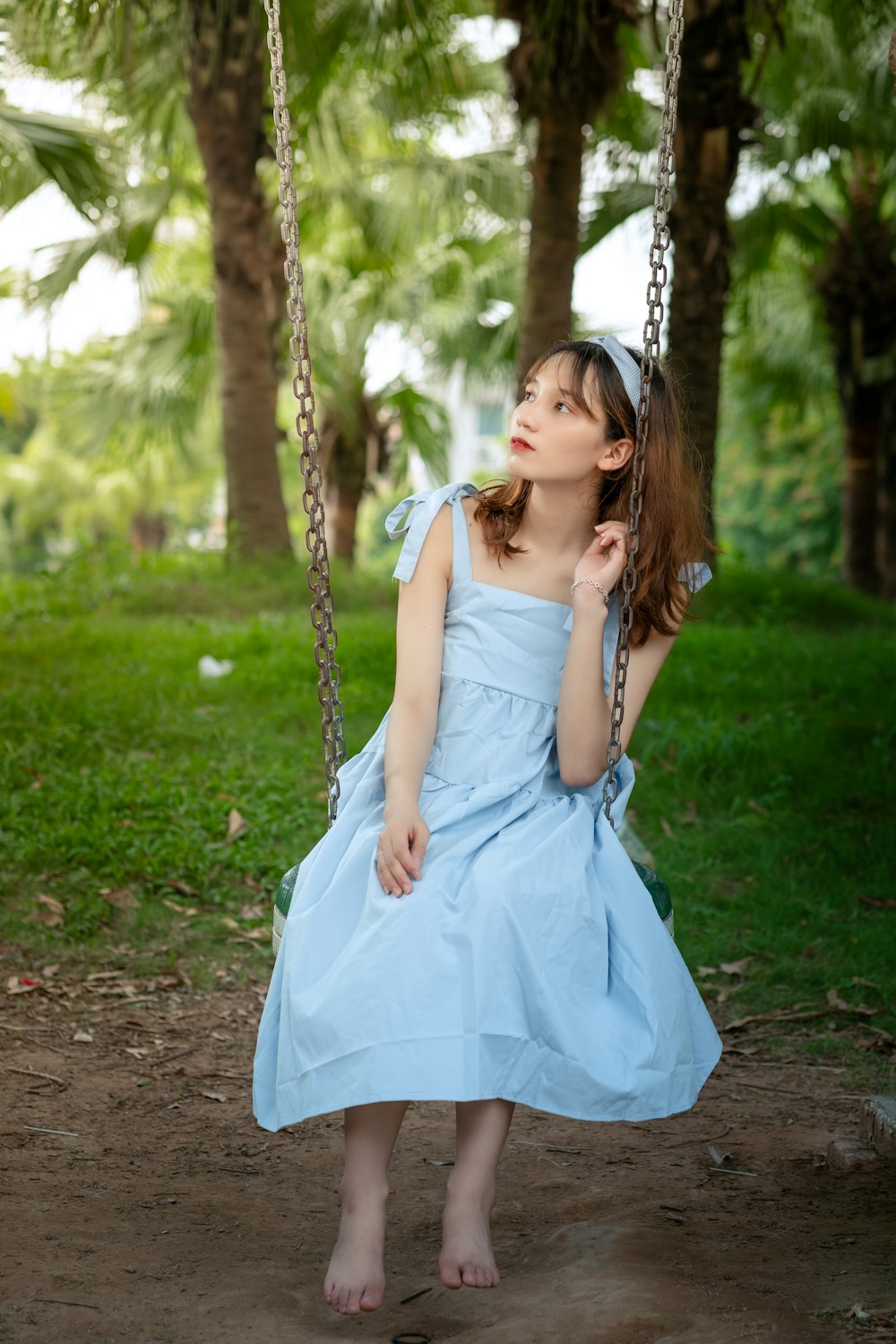 woman in white sleeveless dress sitting on swing during daytime