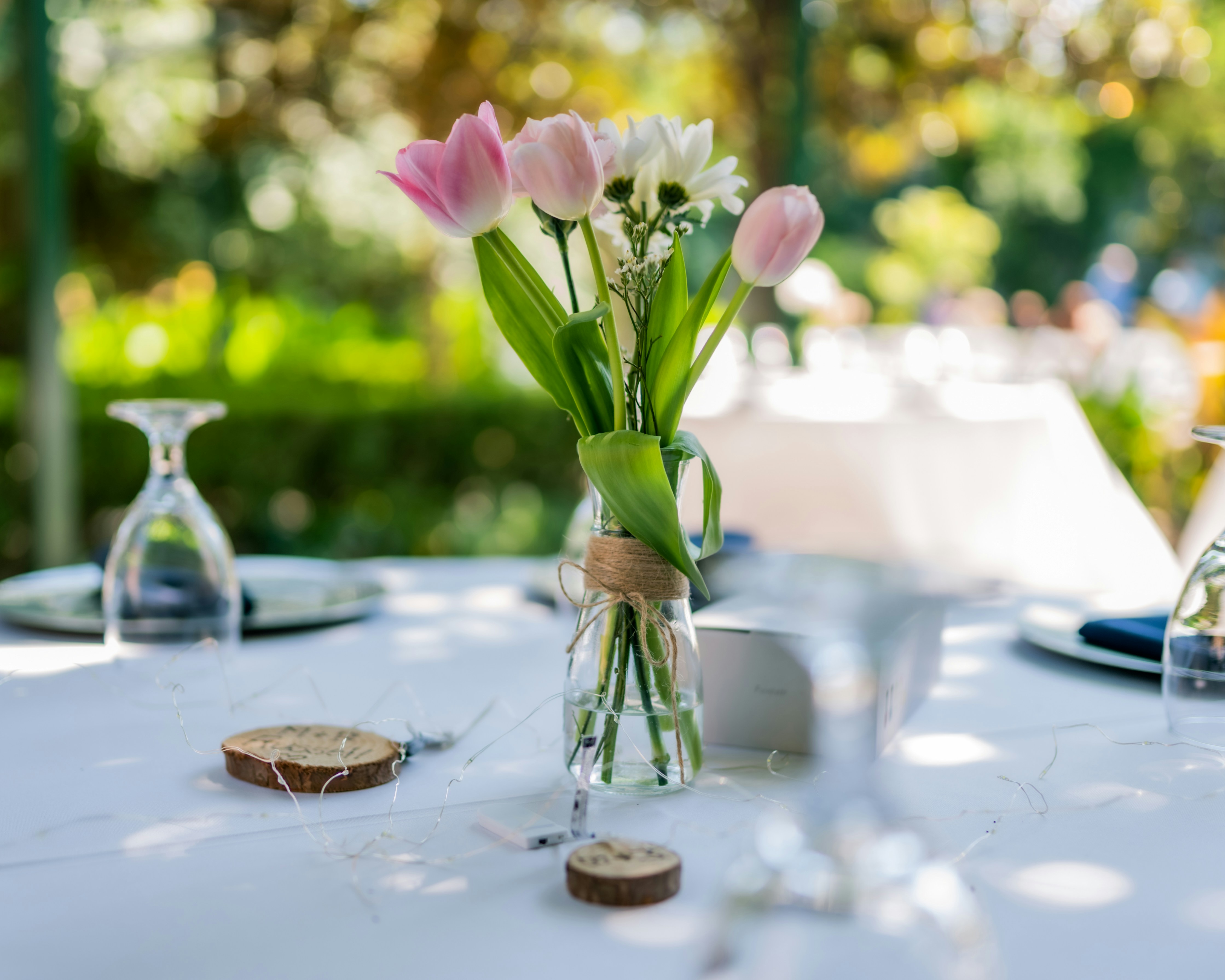 pink and white moth orchids in clear glass vase on white table centerpiece teams background