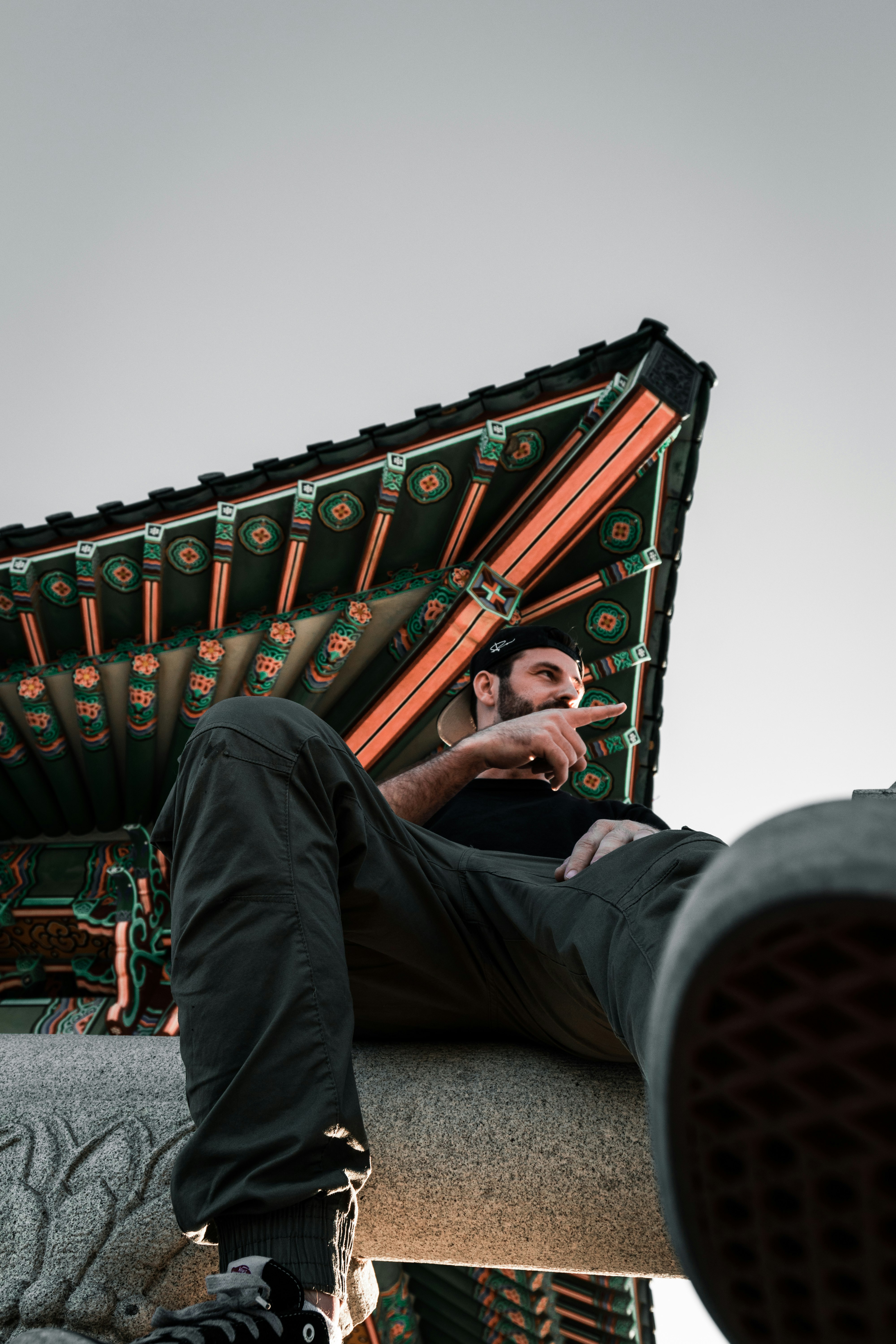 man in black pants sitting on red and black metal bar