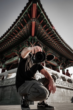 man in black t-shirt and white pants holding black camera