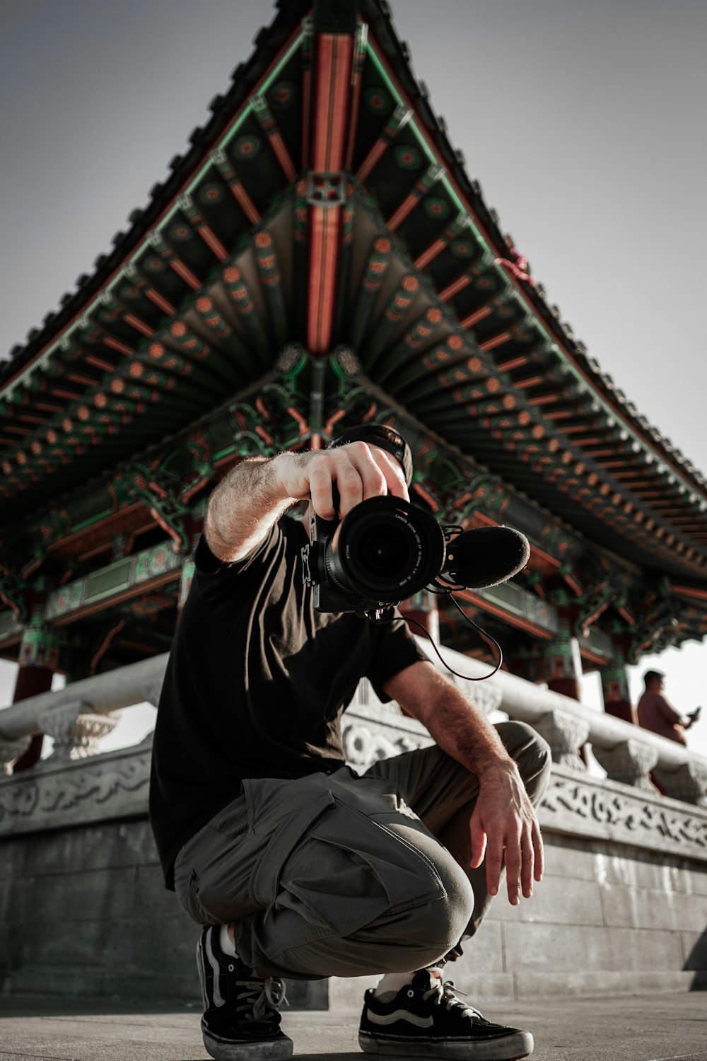 man in black t-shirt and white pants holding black camera