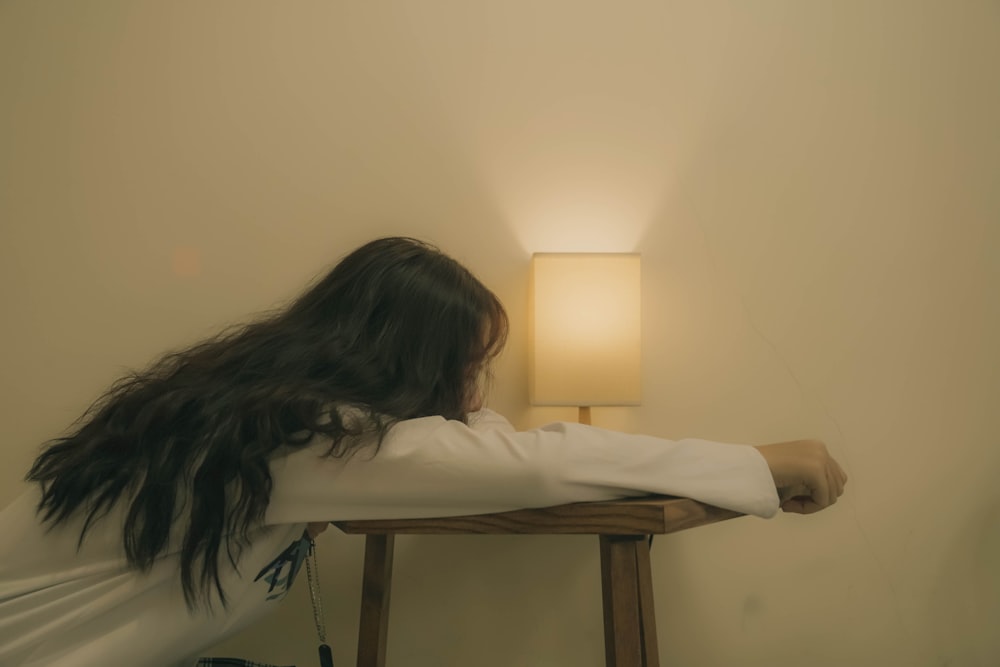 woman lying on bed covering her face with white blanket