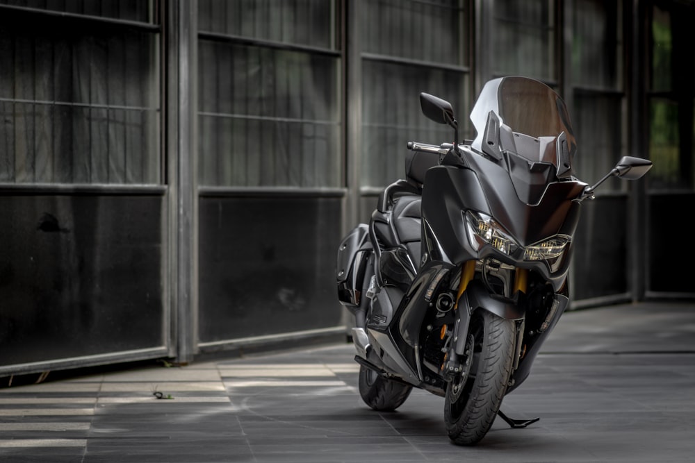 black and silver motorcycle parked on sidewalk during daytime