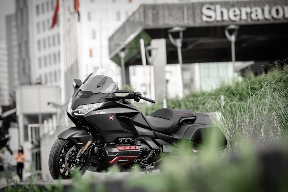 black and red sports bike parked on green grass field during daytime