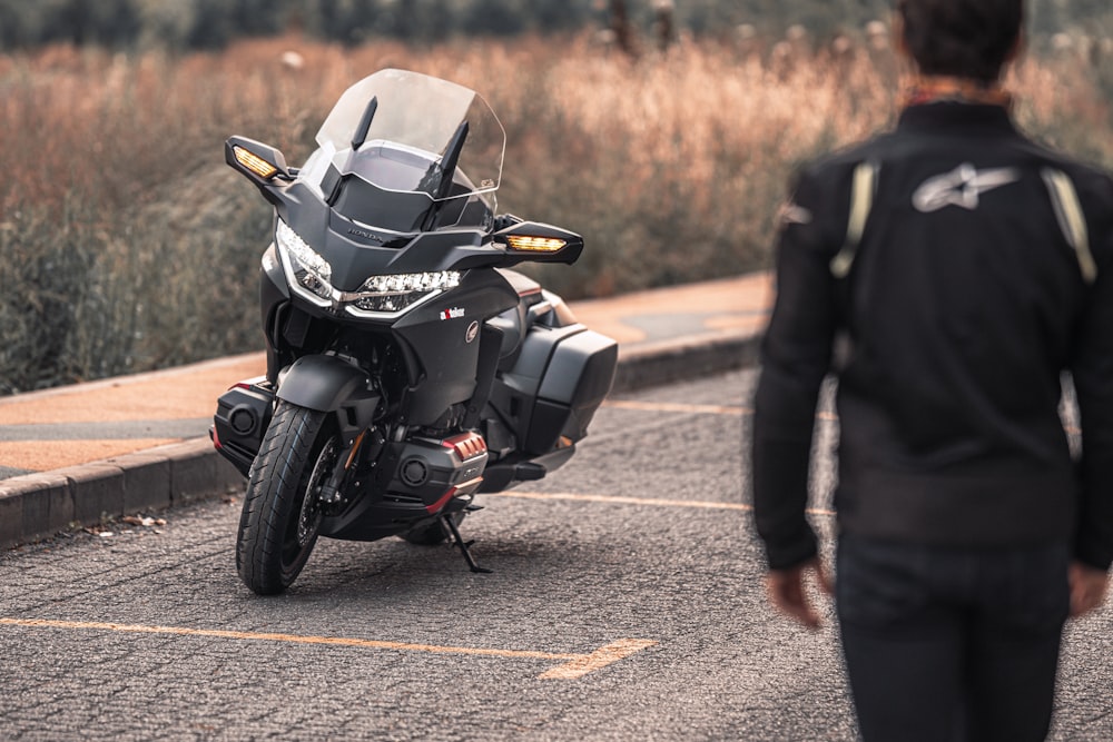 man in black jacket riding black sports bike on road during daytime