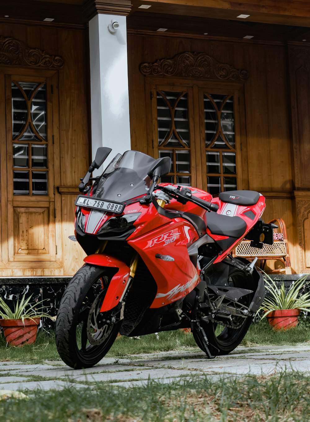 red and black sports bike parked beside brown wooden door