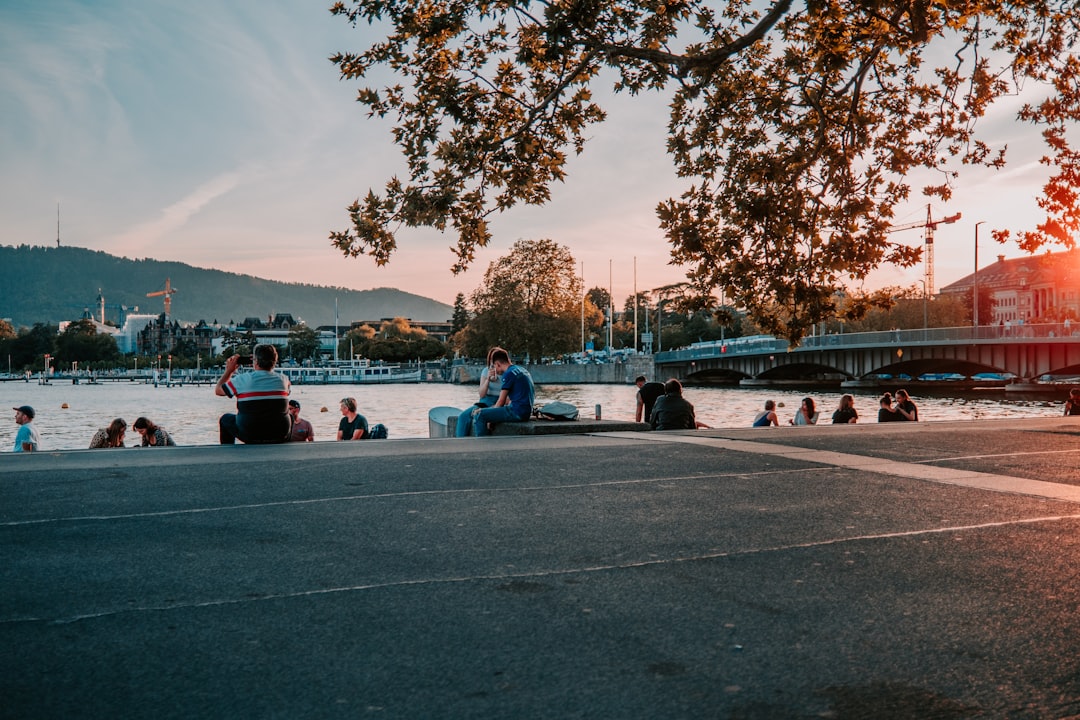 people sitting on gray concrete road near body of water during daytime