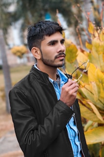 man in black leather jacket holding sunglasses