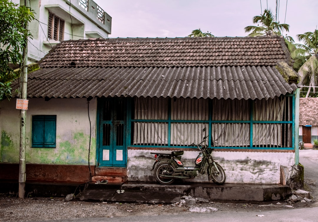 black motorcycle parked beside blue and brown house during daytime