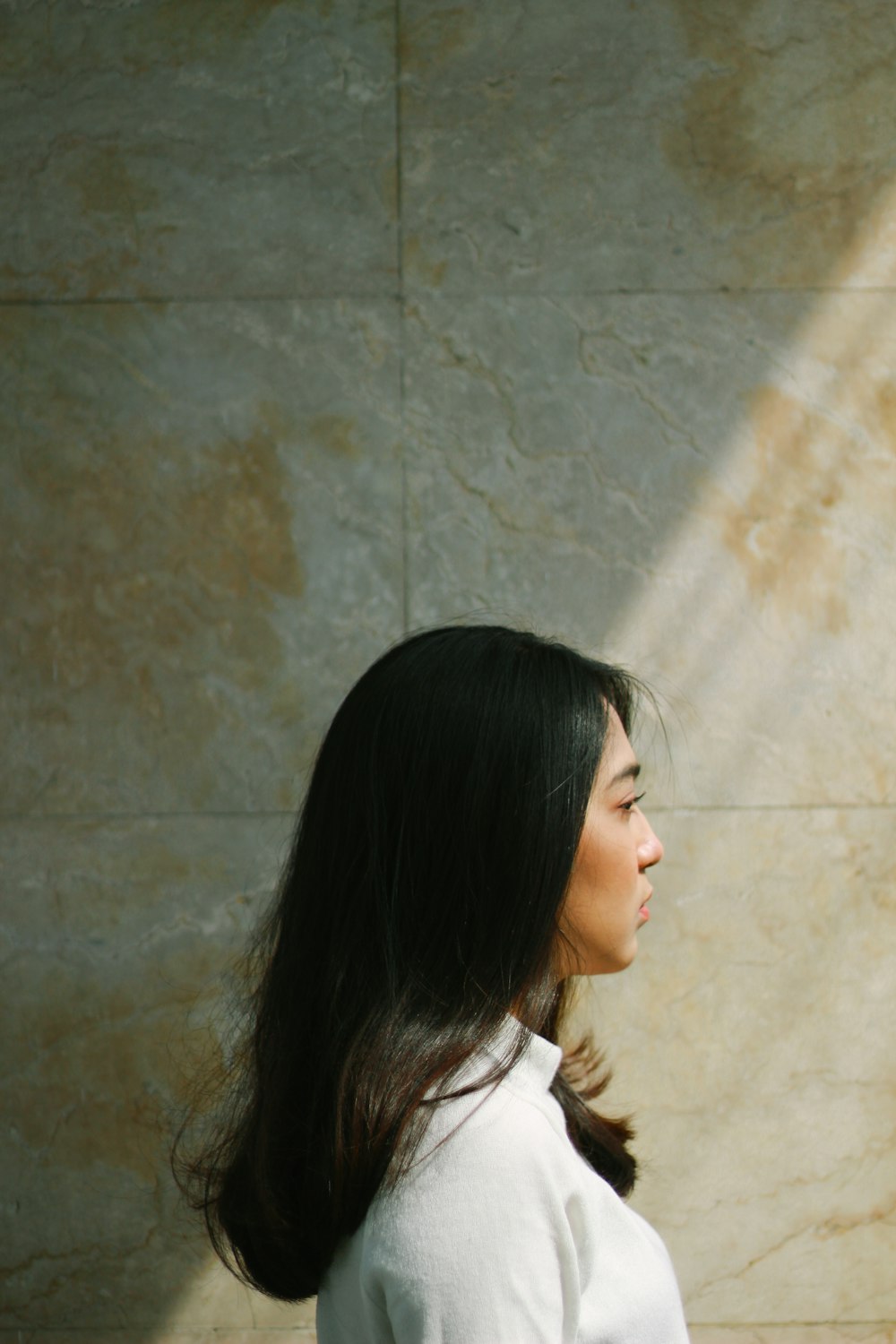 woman in white shirt standing near brown wall