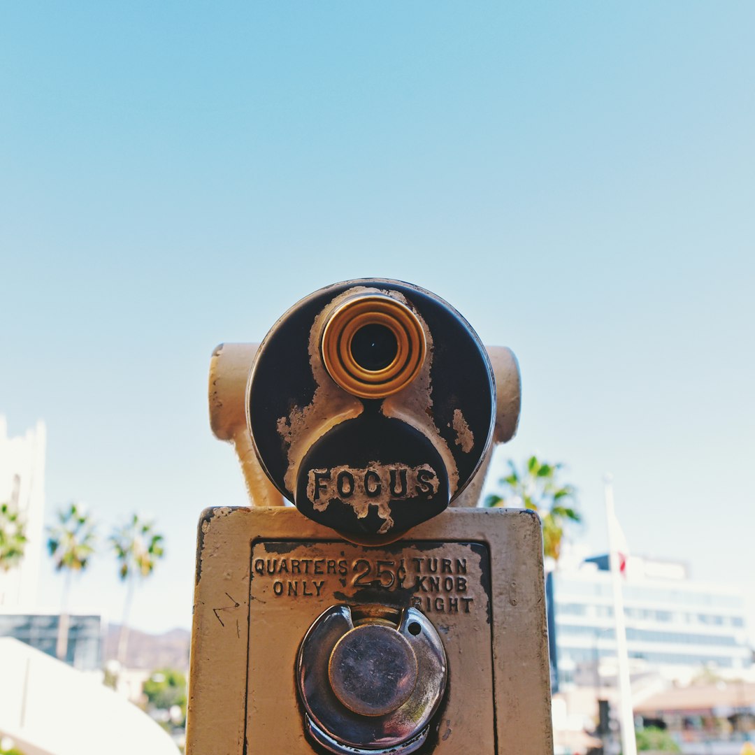 brass and black camera on brown wooden fence during daytime