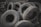 A pile of worn-out tires with various tread patterns stacked in an outdoor setting, surrounded by rocks and debris. The tires appear used and are arranged haphazardly.