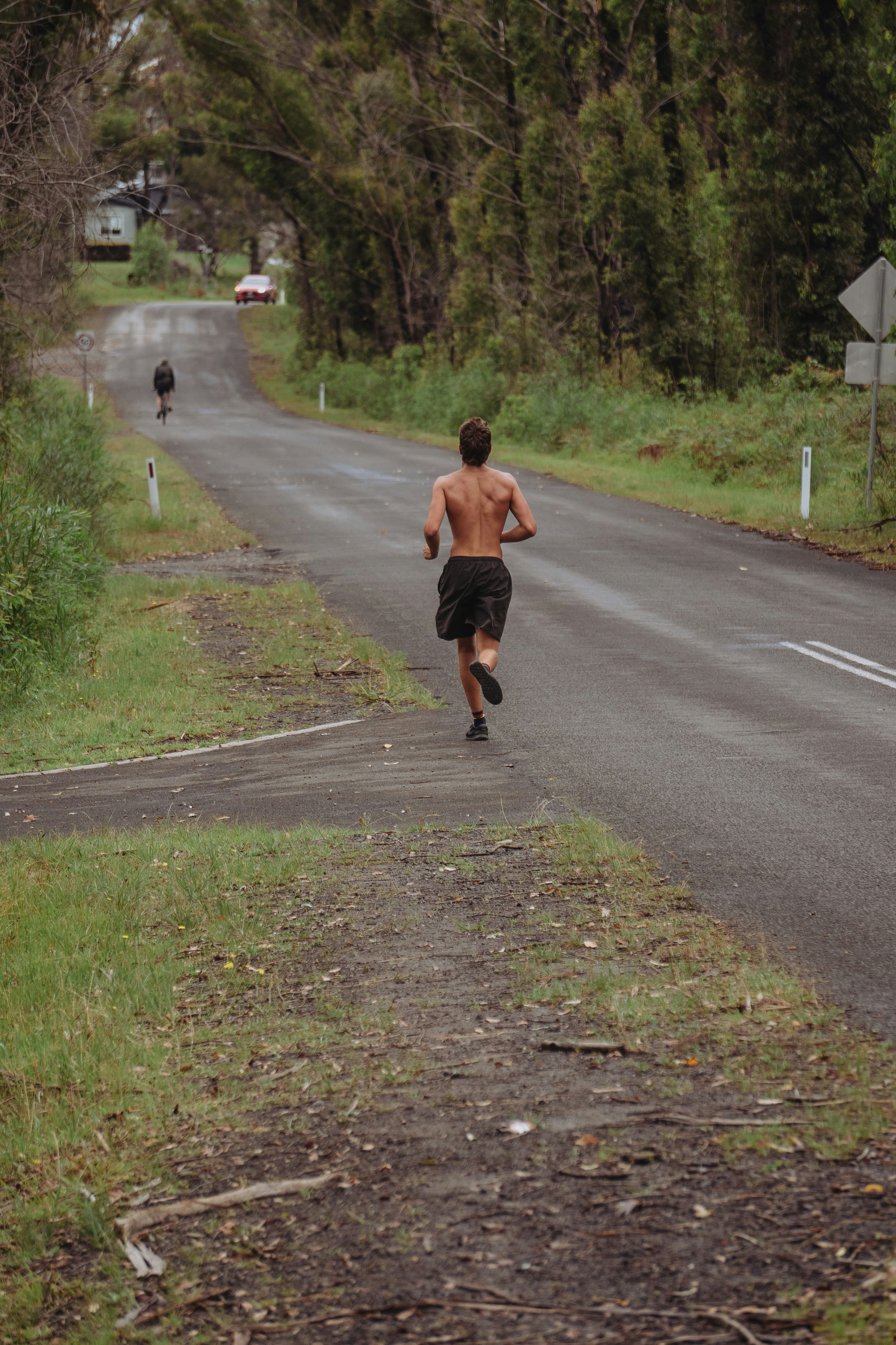 man in brown shirt running on gray asphalt road during daytime