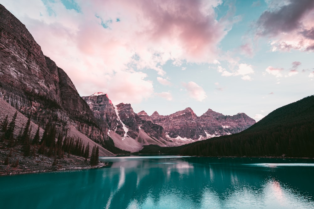 lake near snow covered mountain under cloudy sky during daytime