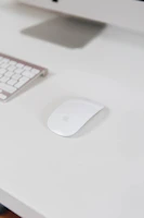 A sleek black wireless mouse beside a laptop on a clean workspace