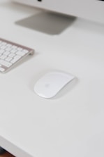 A modern wireless mouse placed next to a laptop on a clean office desk.