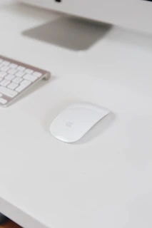 An elegant wireless mouse resting beside a slim laptop on a clean workspace