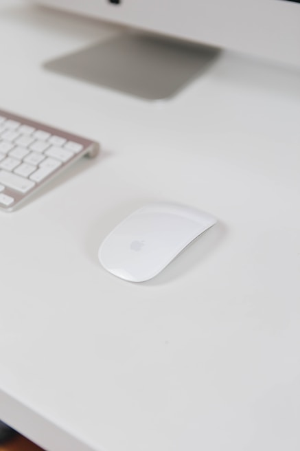 A modern ergonomic mouse resting beside a laptop with a clean workspace background