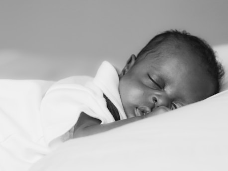 baby in white shirt lying on bed
