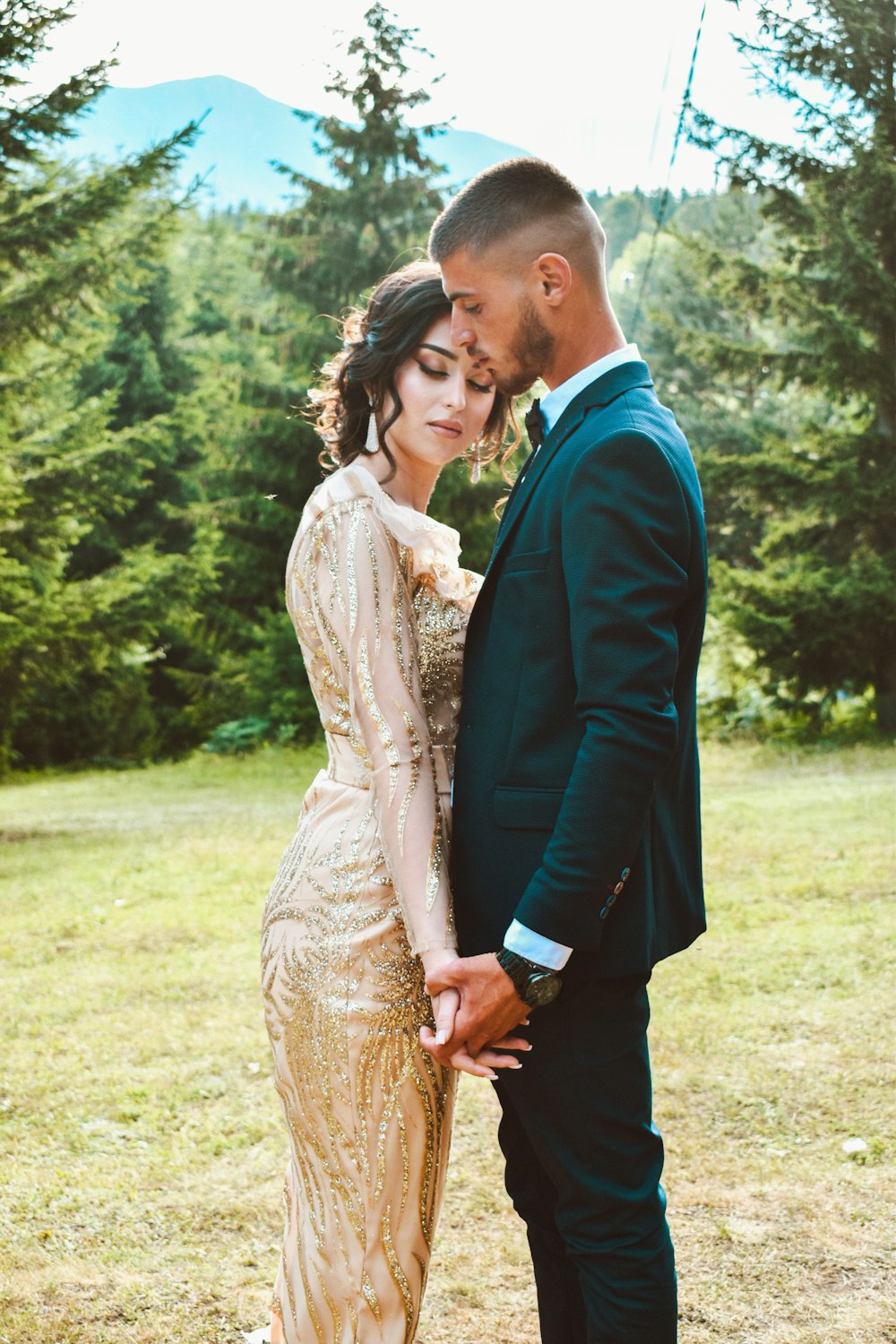 man in blue suit and woman in brown dress standing on green grass field during daytime