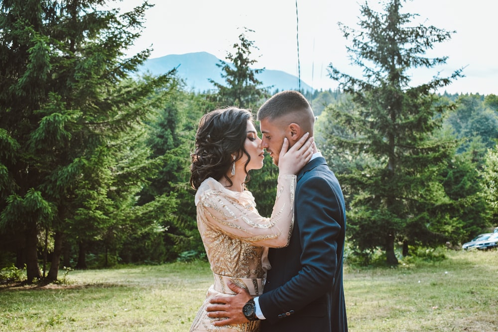 man and woman kissing on green grass field during daytime