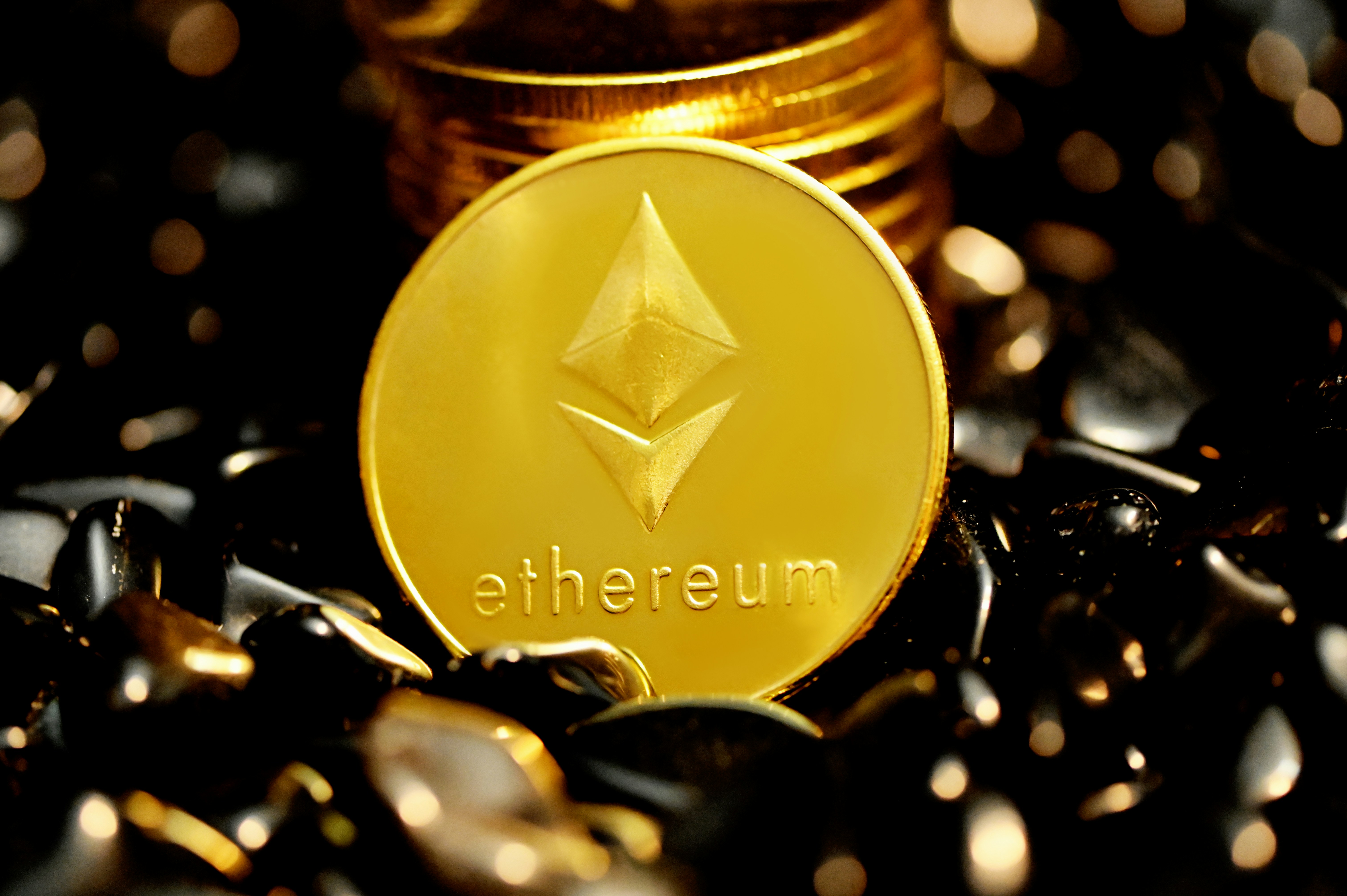 A pile of ethereum coins on black stones