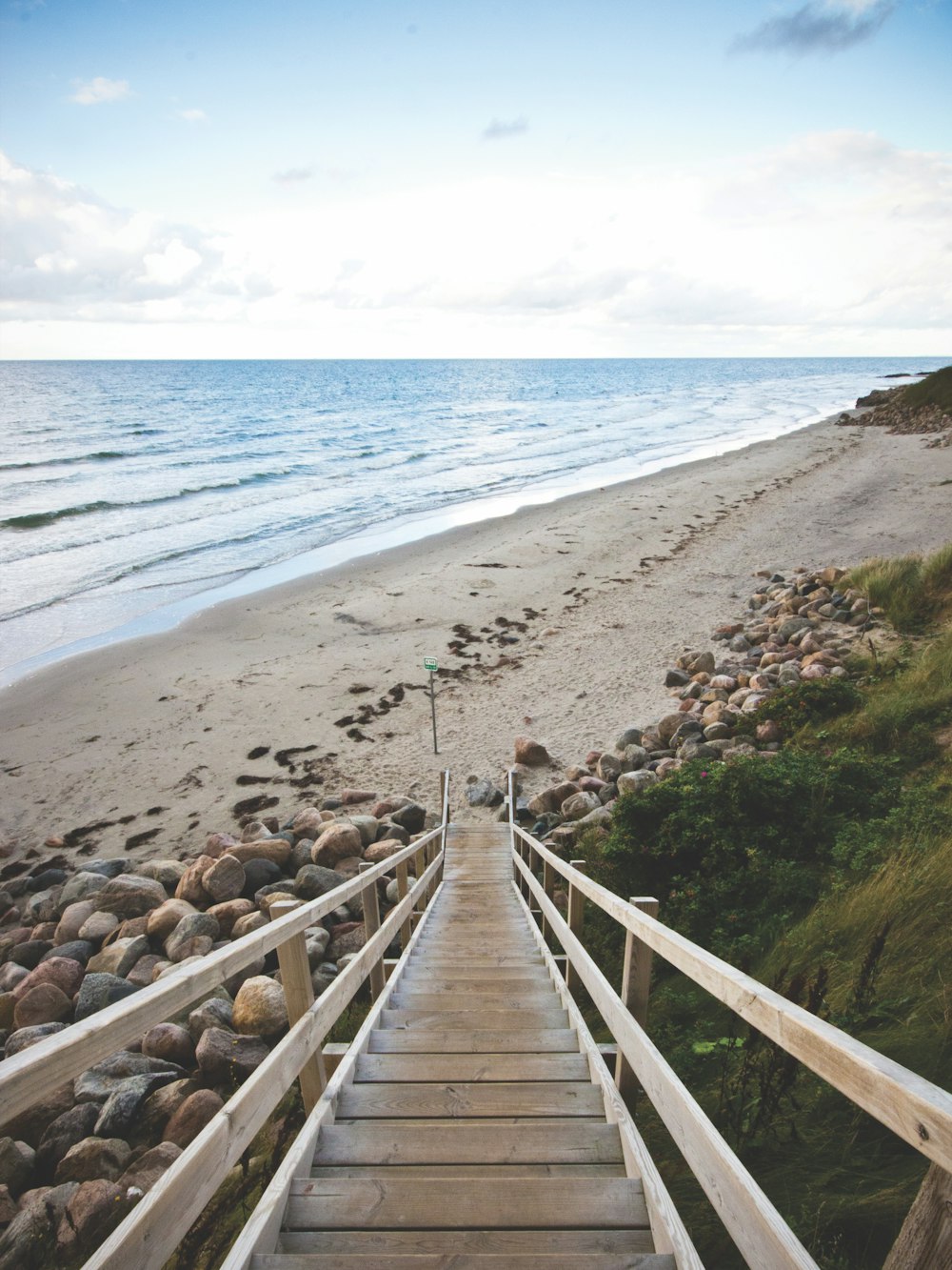 people walking on wooden bridge near beach during daytime