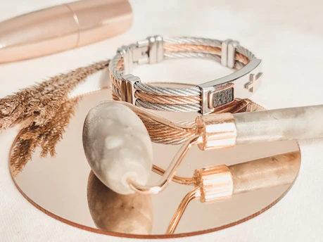 silver and gold bracelet on white textile