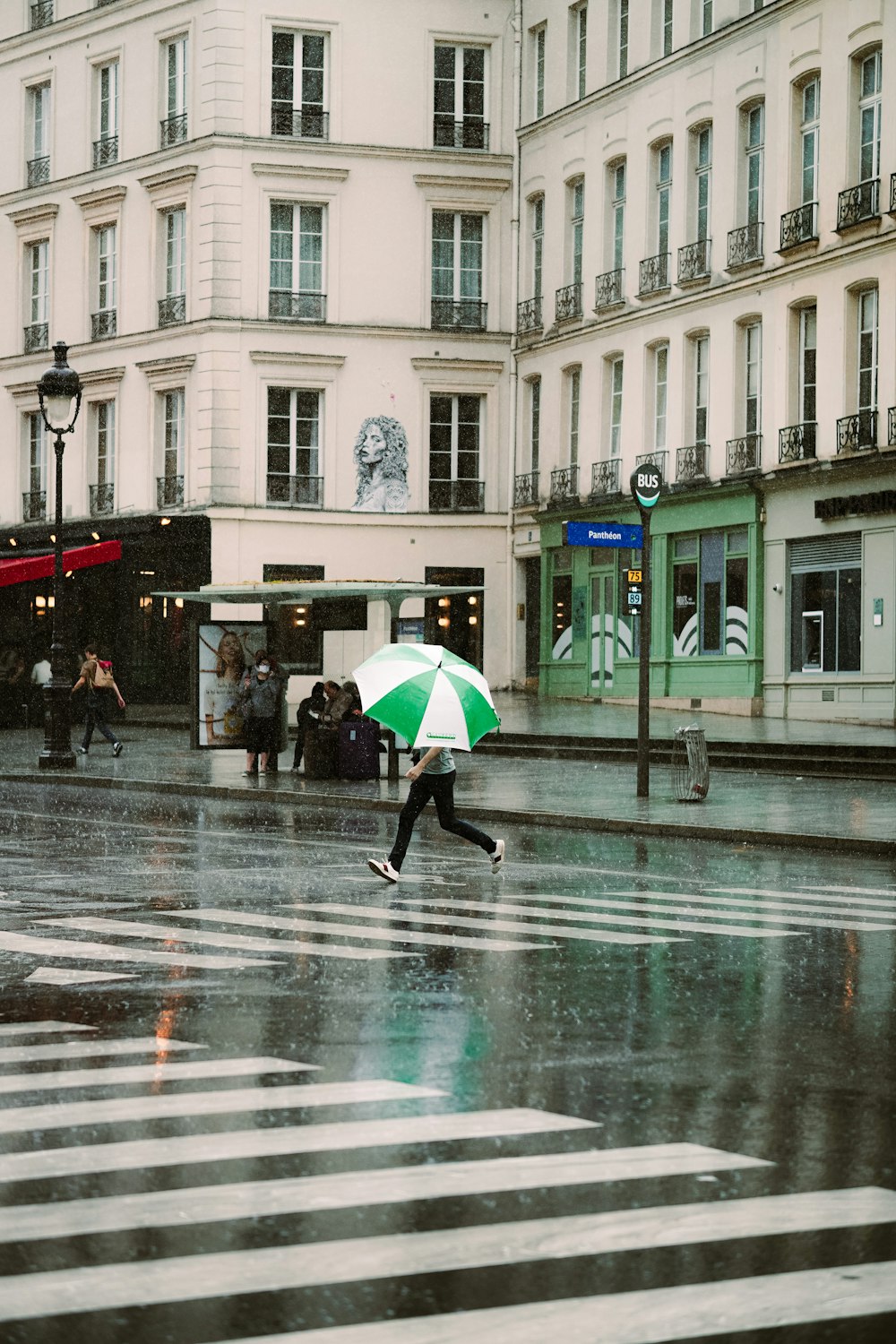 person holding green umbrella walking on street during daytime