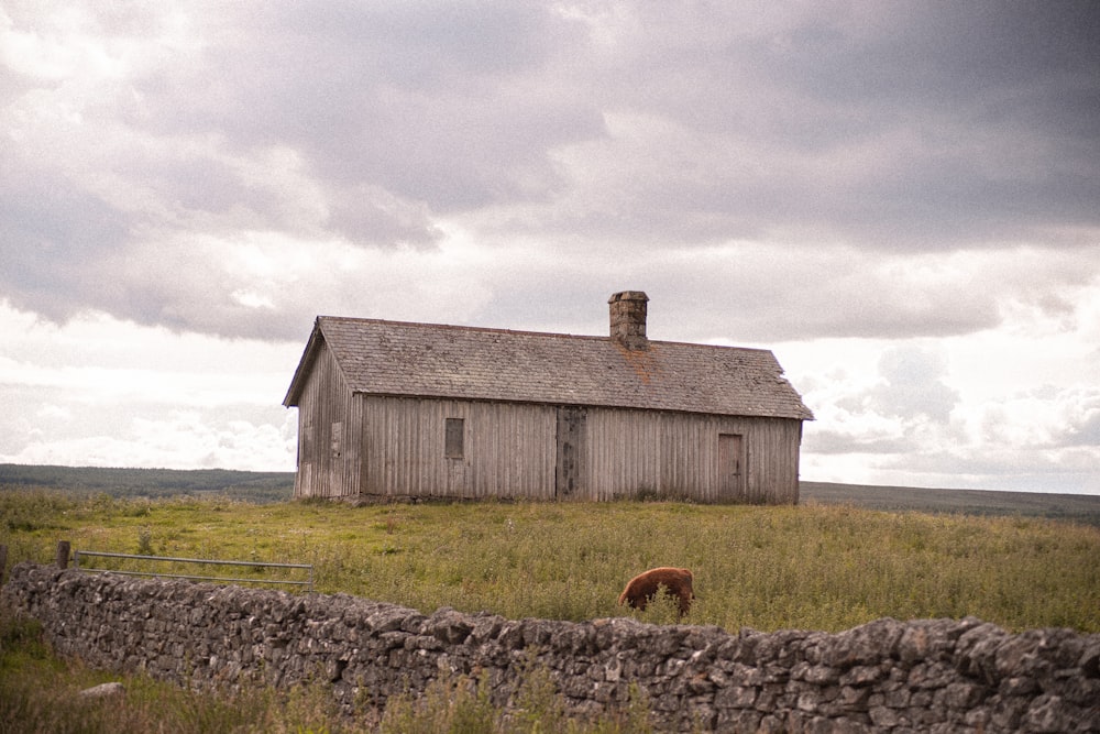 brown wooden barn on green grass field under white cloudy sky during daytime