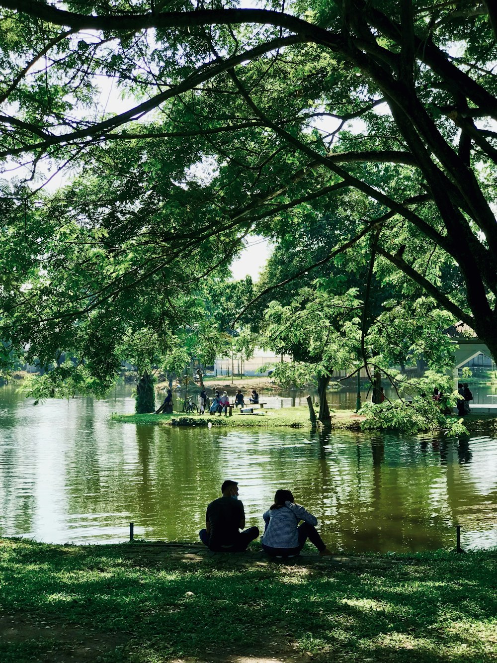 man and woman sitting on bench near body of water during daytime