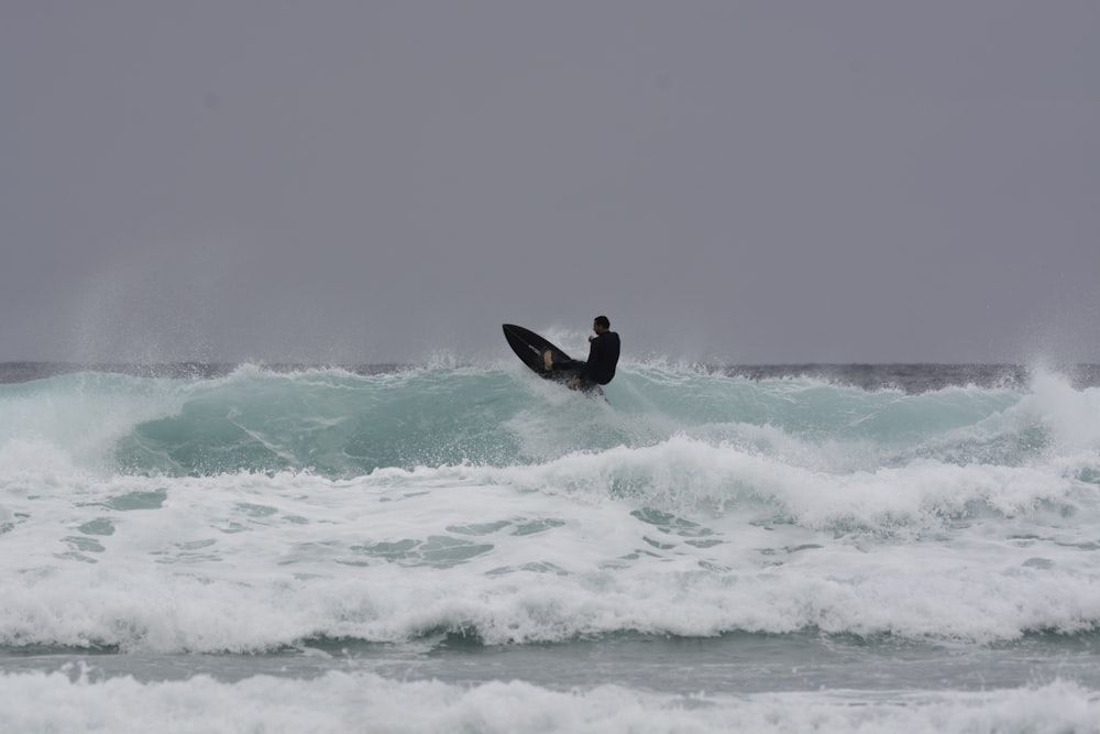 man surfing on sea waves during daytime