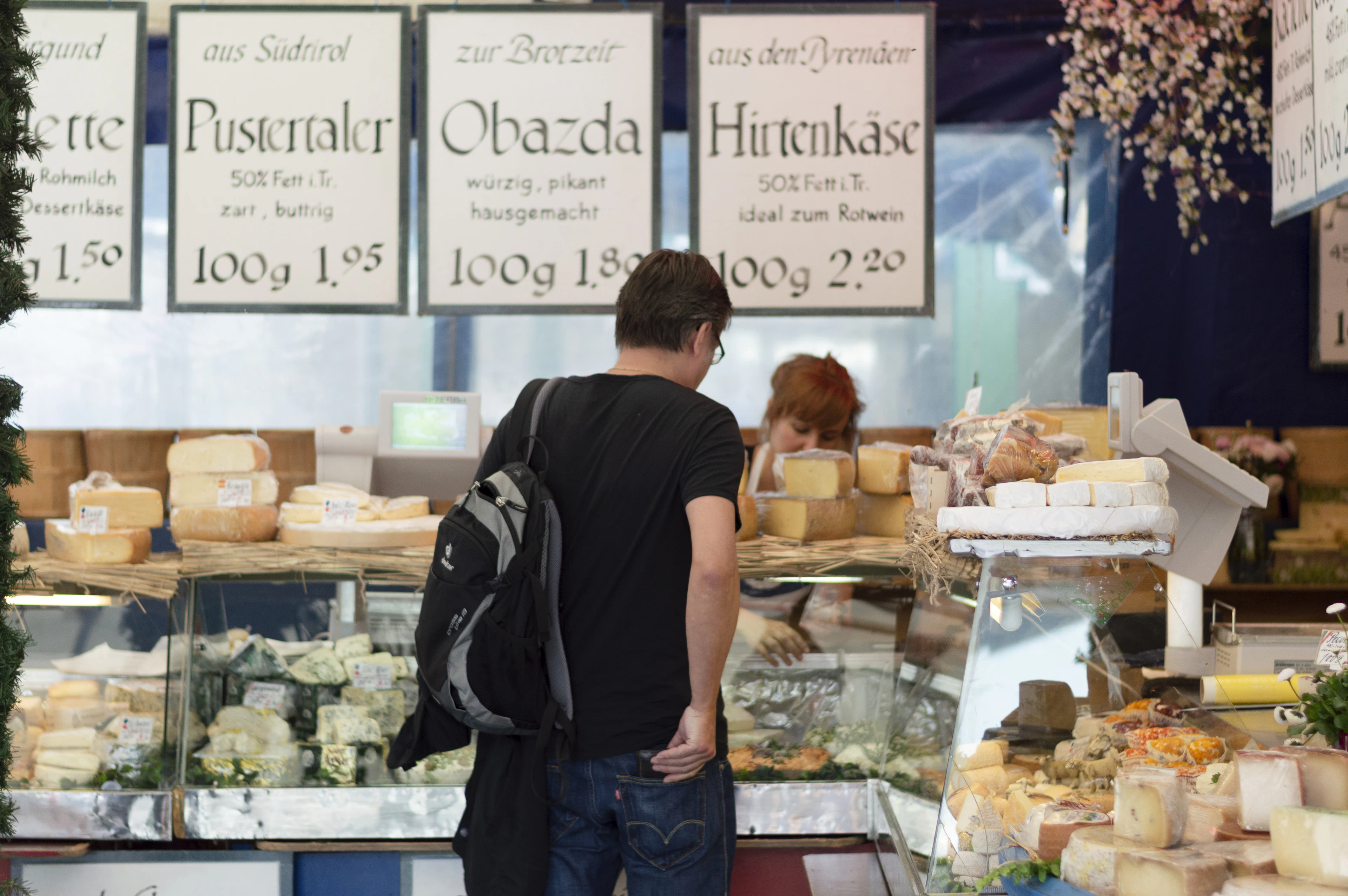 A cheese counter at Munich's Viktualienmarkt, wheels and wedges behind glass with handwritten German price cards