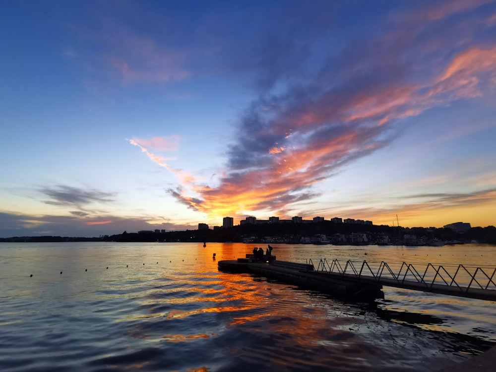 silhouette of bridge over water during sunset