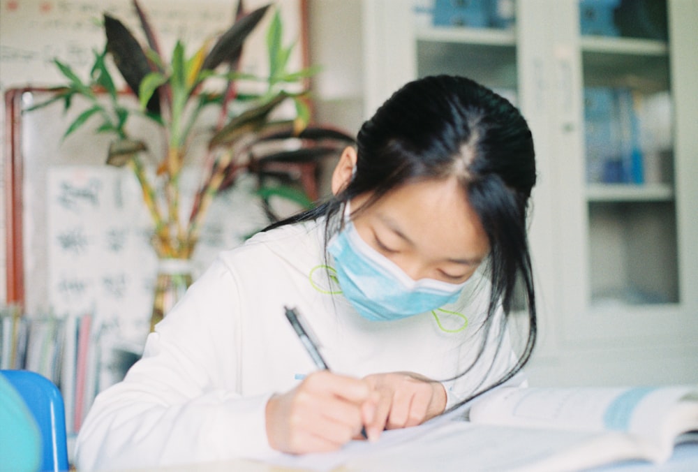 woman in white long sleeve shirt writing on white paper