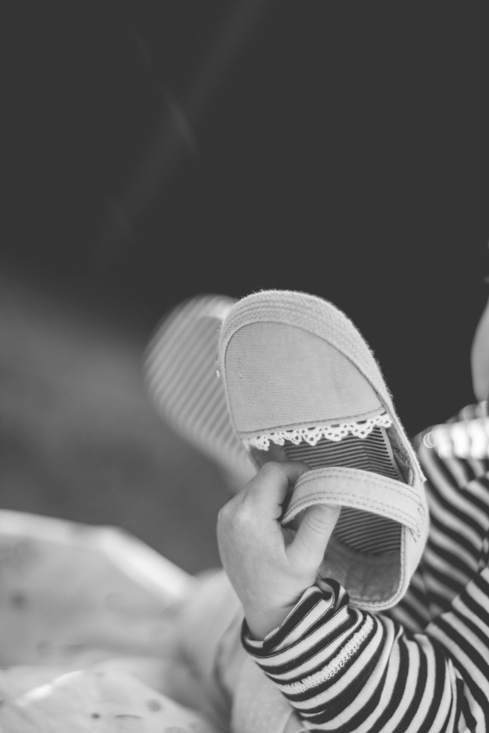 grayscale photo of person wearing black and white stripe slide sandals