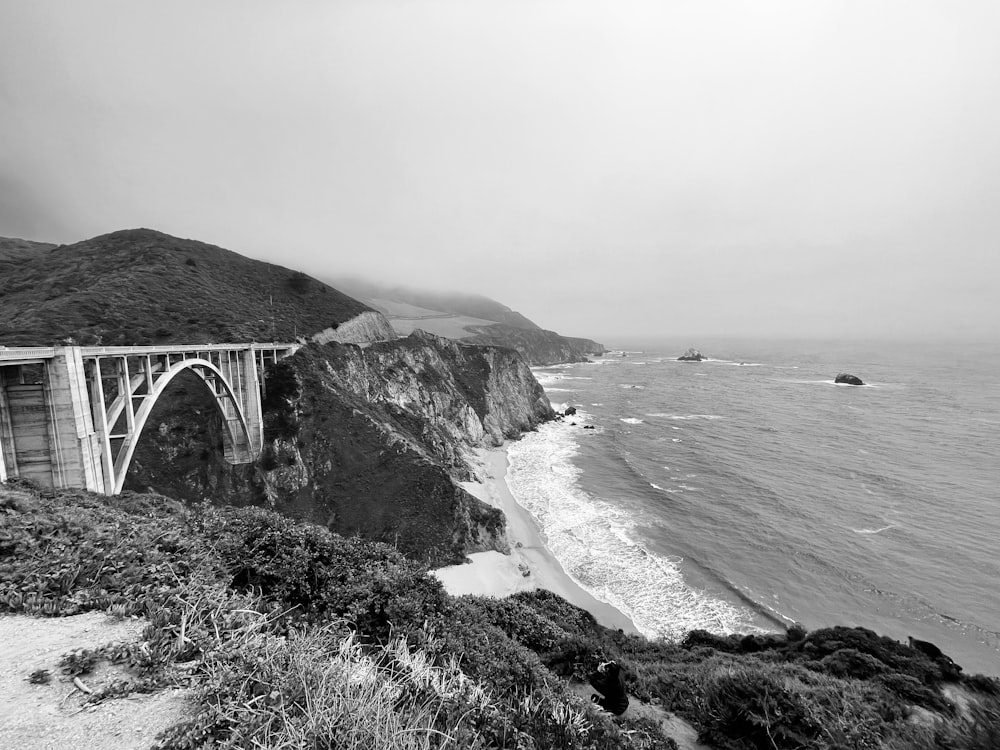 grayscale photo of bridge over the sea