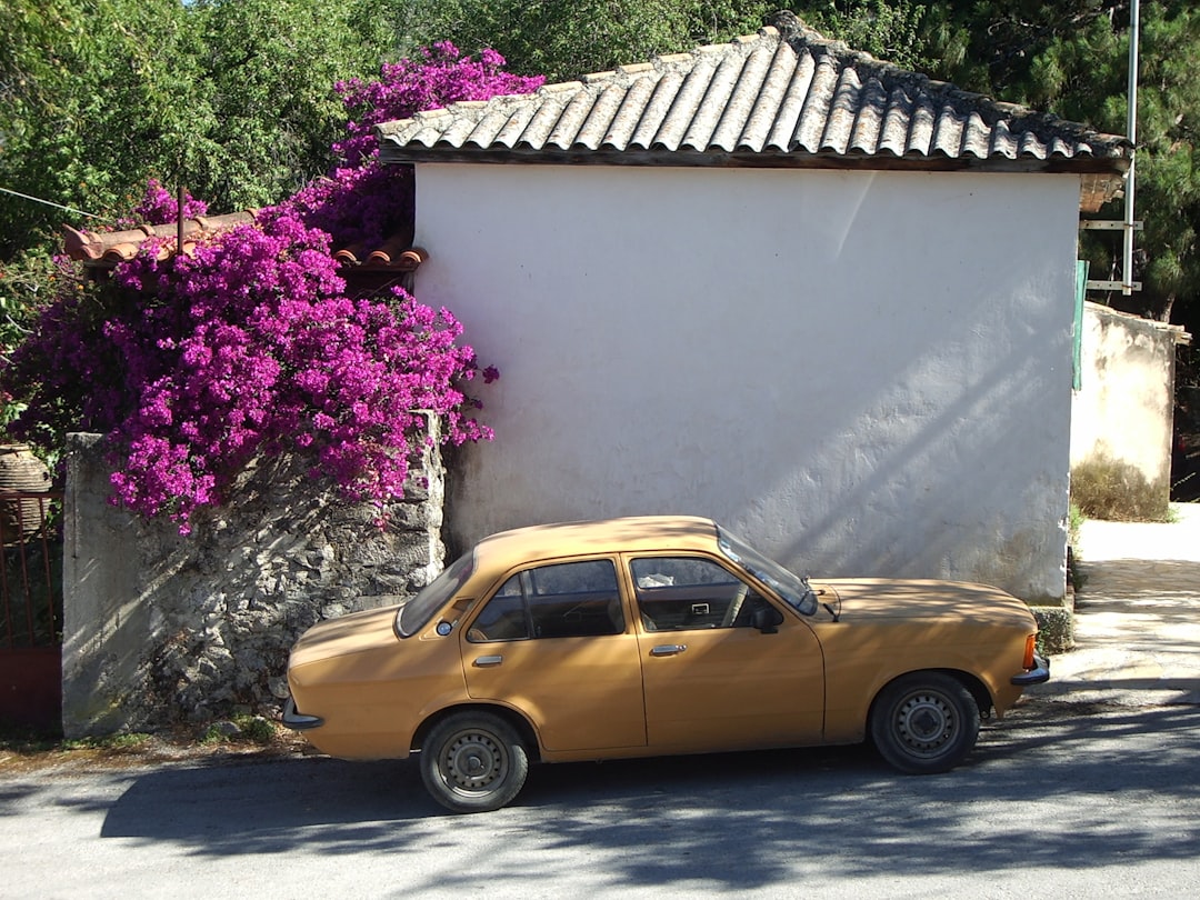 yellow sedan parked beside white concrete house,