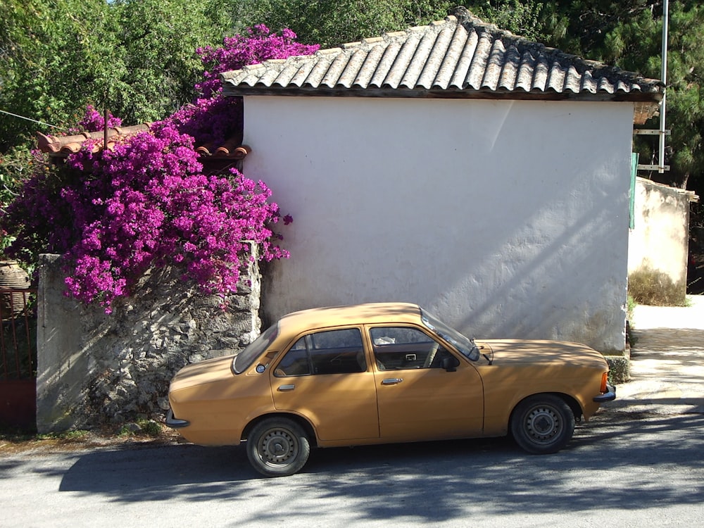 yellow sedan parked beside white concrete house