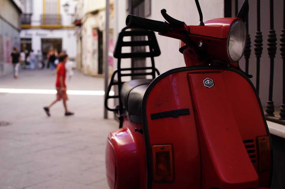 red and black motor scooter parked on the street during daytime